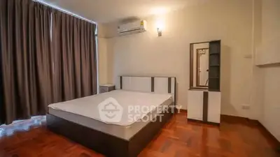Spacious bedroom with modern furniture and wooden flooring