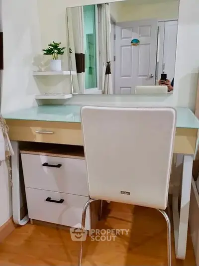Modern study area with sleek desk, mirror, and white chair in cozy apartment.