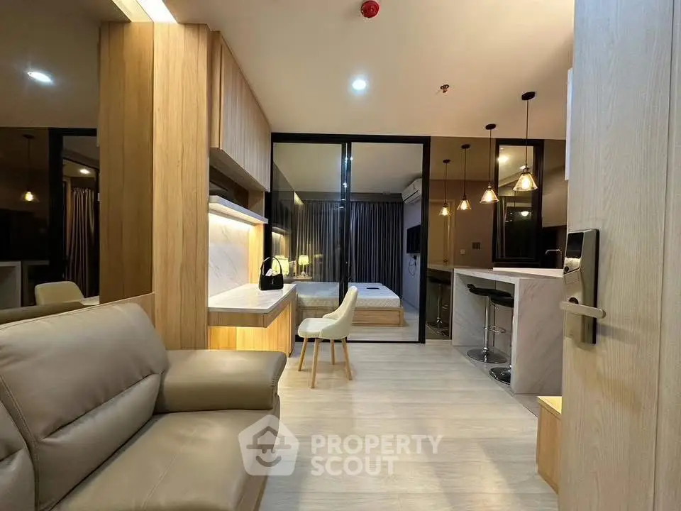 Modern open-plan living room with sleek kitchen and cozy bedroom in a stylish apartment.