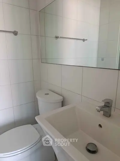 Modern bathroom with sleek white tiles and contemporary fixtures.