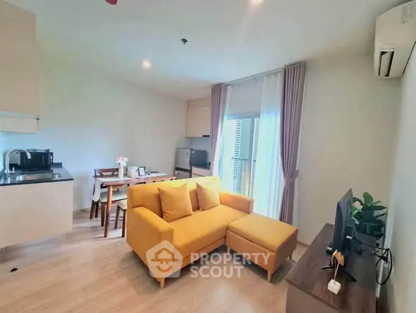 Modern living room with vibrant yellow sofa and open kitchen layout in a cozy apartment.