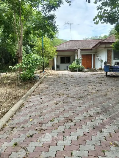 Charming single-story home with spacious driveway and lush greenery, perfect for serene living.