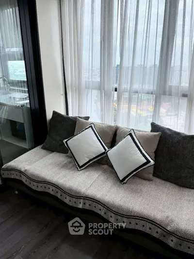 Stylish living room with cozy sofa and city view through sheer curtains.