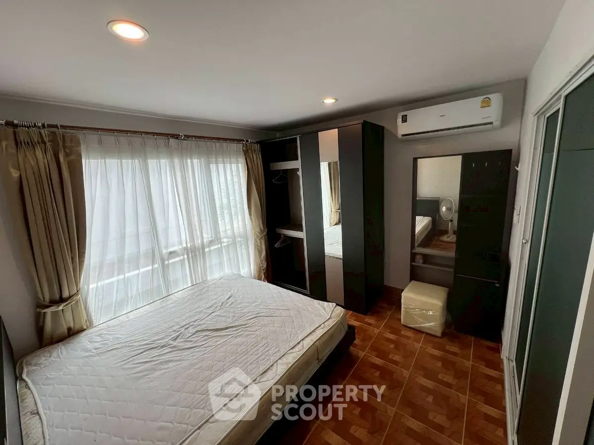 Spacious bedroom with large window and modern furnishings