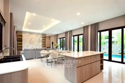 Luxurious open-plan living room with modern kitchen and pool view, featuring elegant marble accents and ample natural light.