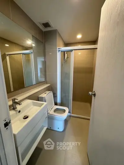 Modern bathroom with sleek fixtures and spacious shower in contemporary apartment.