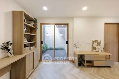 Modern living room with wooden furniture and sliding glass doors to a serene outdoor space.