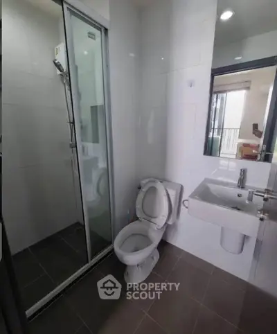 Modern bathroom with glass shower and sleek fixtures in contemporary apartment.