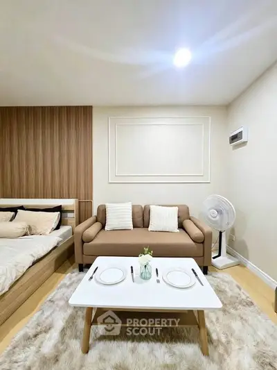 Cozy studio apartment with modern decor, featuring a comfortable sofa and stylish coffee table.