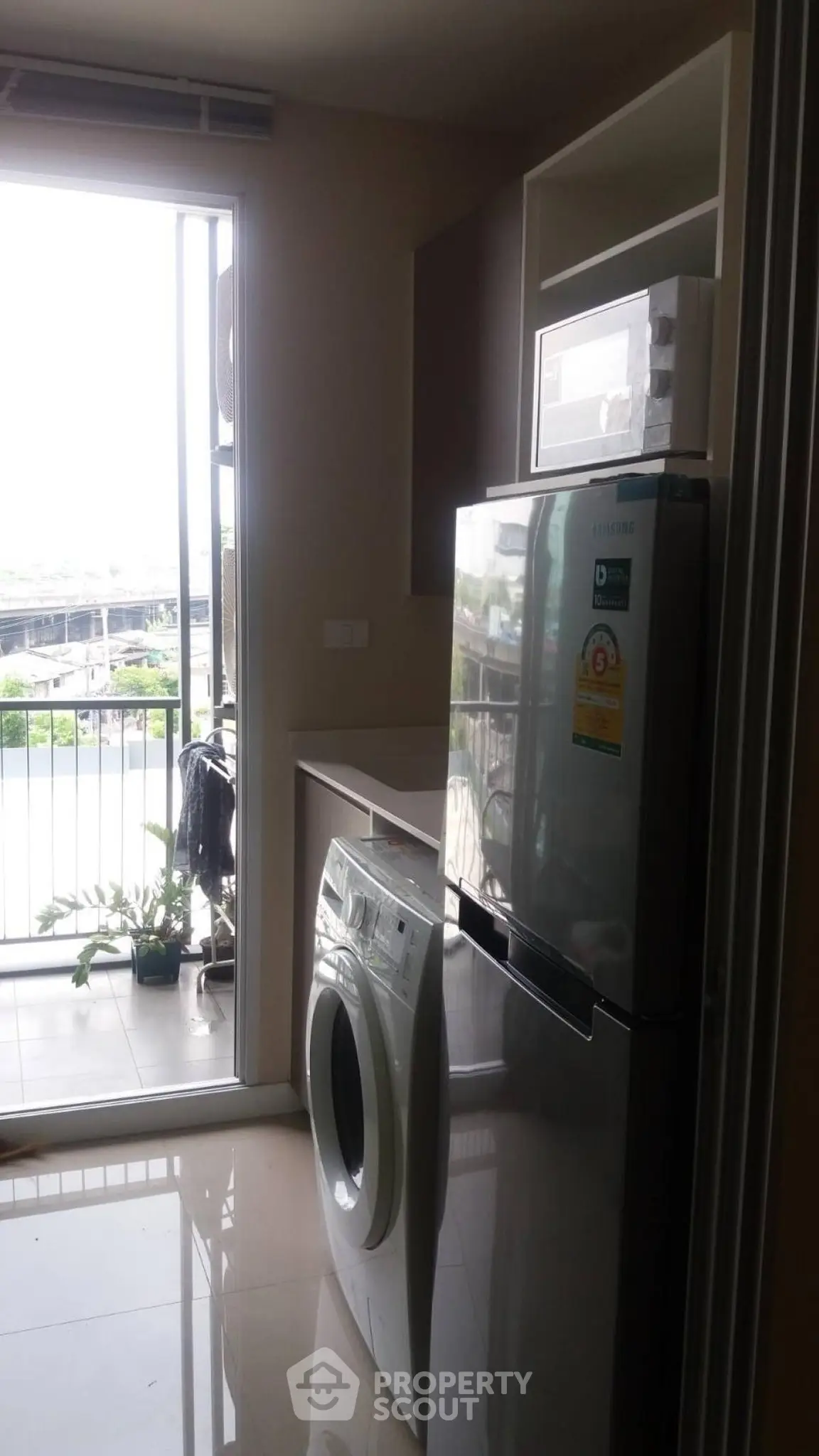 Modern kitchen with washing machine and fridge near balcony with view.