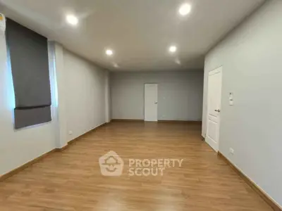 Spacious empty room with wooden flooring and modern lighting, perfect for customization.