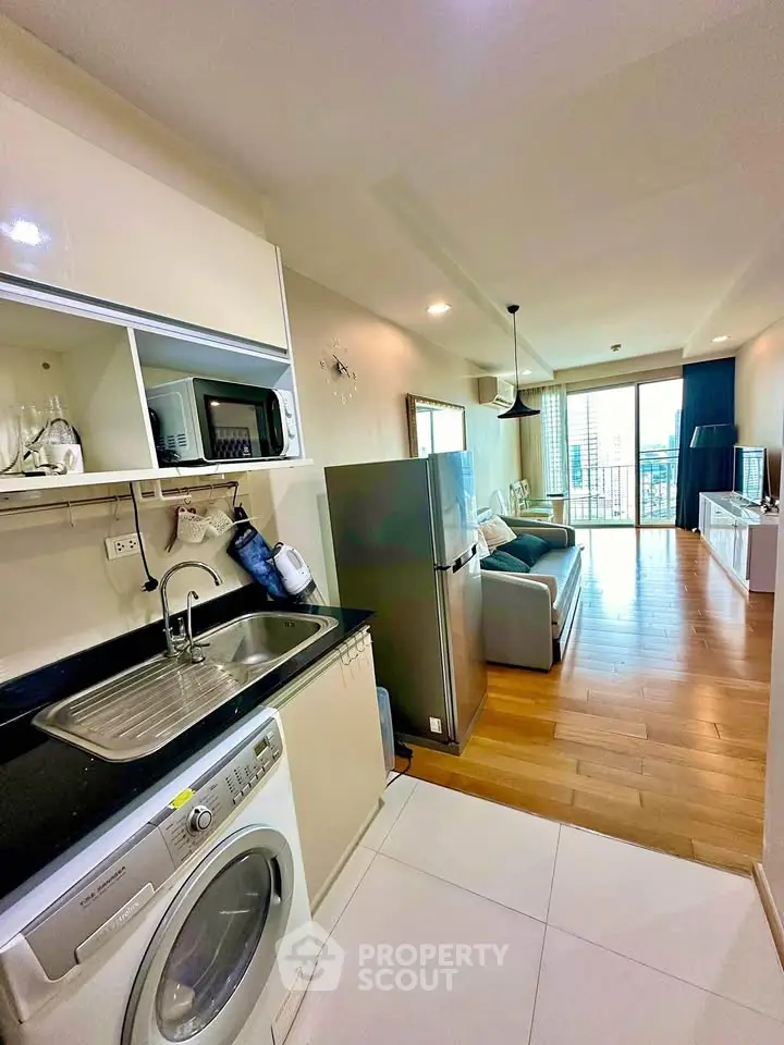 Modern open-plan kitchen and living room with city view, featuring sleek appliances and wooden flooring.