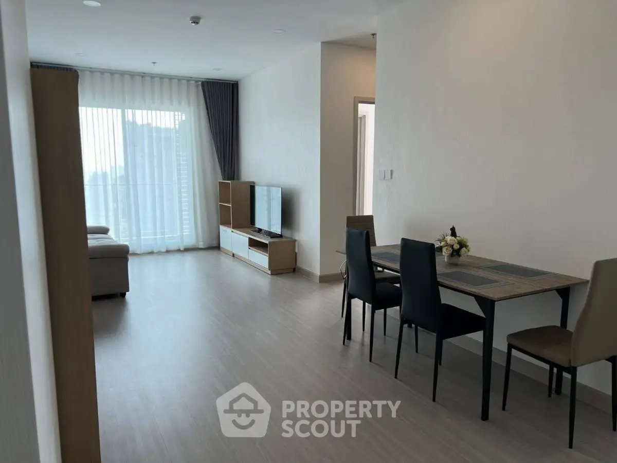 Spacious modern living room with dining area and large windows offering city views.