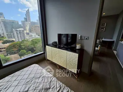 Modern bedroom with city view, featuring sleek TV stand and large window overlooking urban skyline.