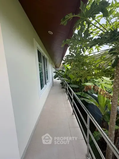 Charming narrow balcony with lush greenery and sleek railing, perfect for a serene outdoor escape.