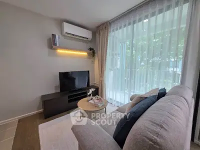 Modern living room with cozy sofa, TV, and large window leading to balcony with greenery view.