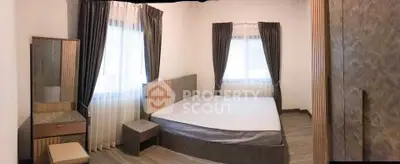 Spacious bedroom with modern furnishings and large windows for natural light.