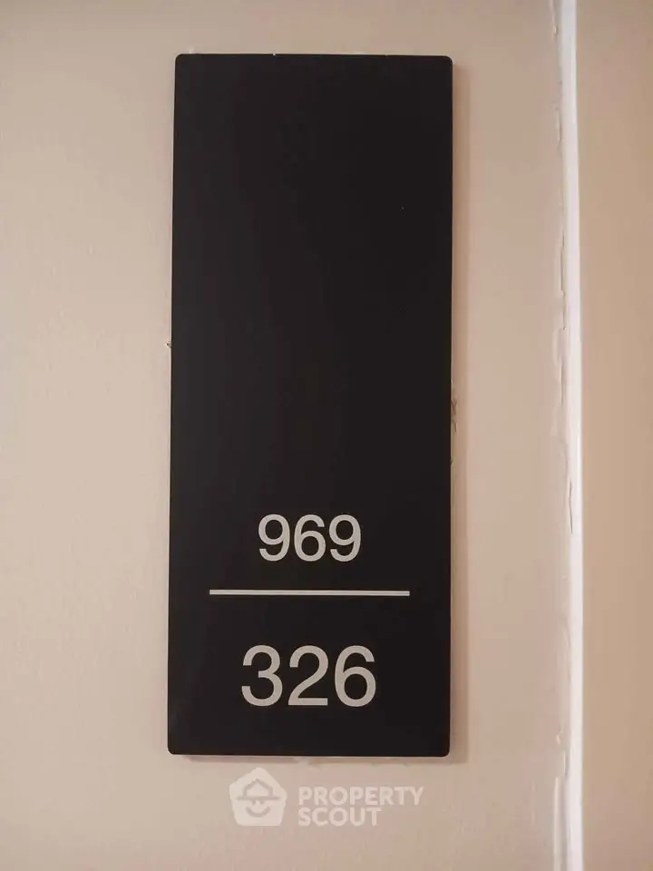 Modern apartment door number sign with sleek black design and white numbers.