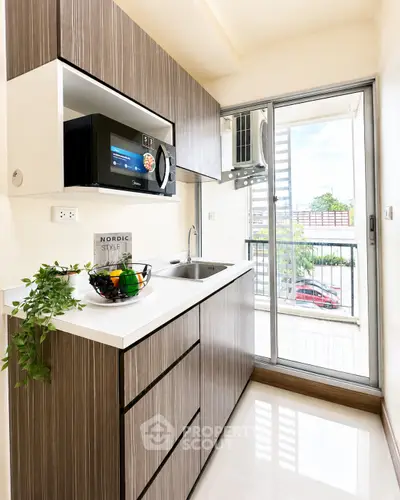 Modern kitchen with sleek cabinetry and balcony view in a stylish apartment.