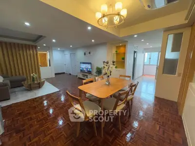 Spacious open-plan living and dining area with elegant lighting and wooden flooring.