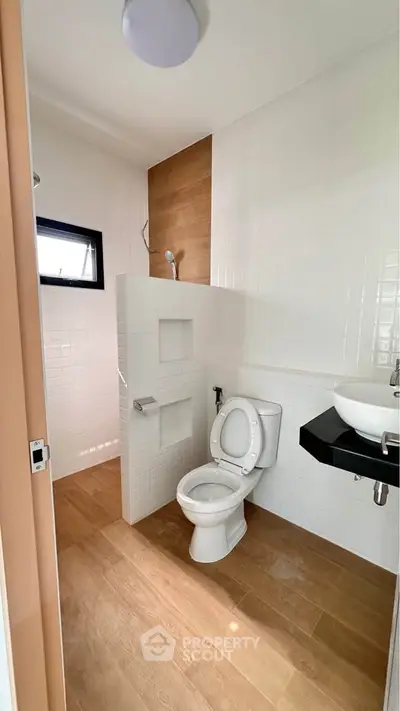 Modern bathroom with wooden accents and sleek fixtures, featuring a toilet and stylish sink.