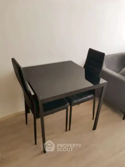 Modern dining area with sleek black table and chairs on wooden flooring.