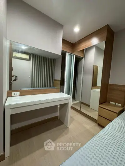 Modern bedroom with mirrored wardrobe and sleek vanity in stylish apartment.
