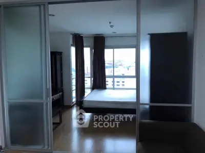 Modern bedroom with large windows and sliding glass doors in urban apartment.