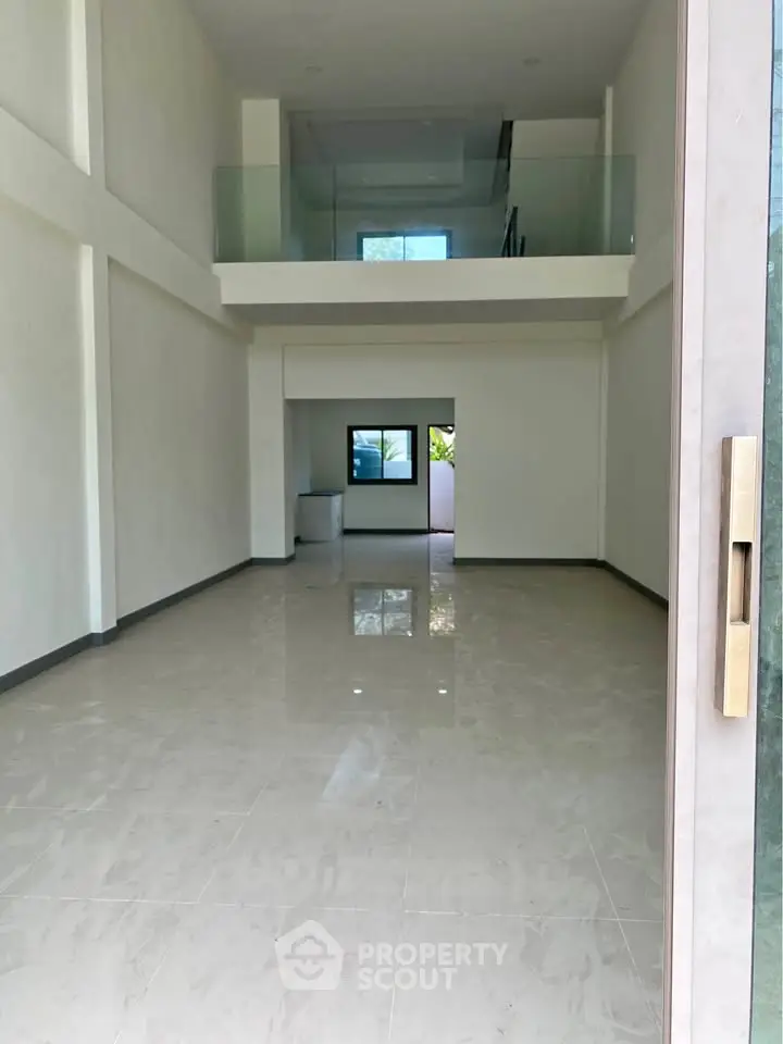 Spacious modern interior with high ceilings and mezzanine, perfect for versatile living or office space.