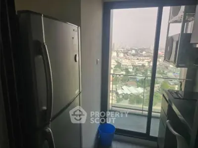 Modern kitchen with balcony view and stainless steel appliances in high-rise apartment.