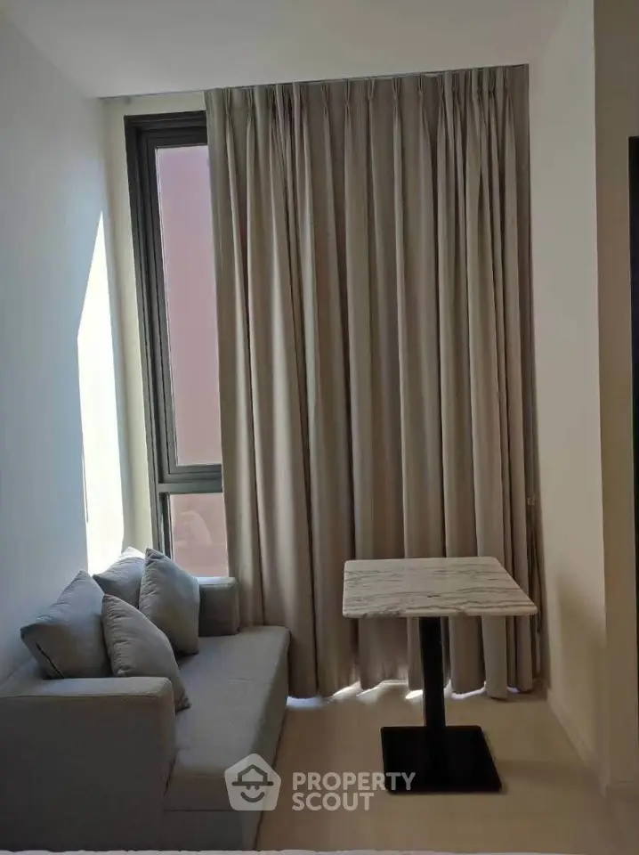 Cozy living room with modern sofa and marble table by a large window with curtains.