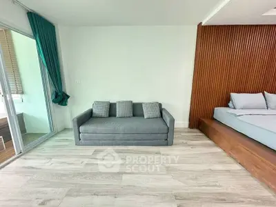 Modern living space with stylish sofa and bed, featuring wooden accents and large window for natural light.