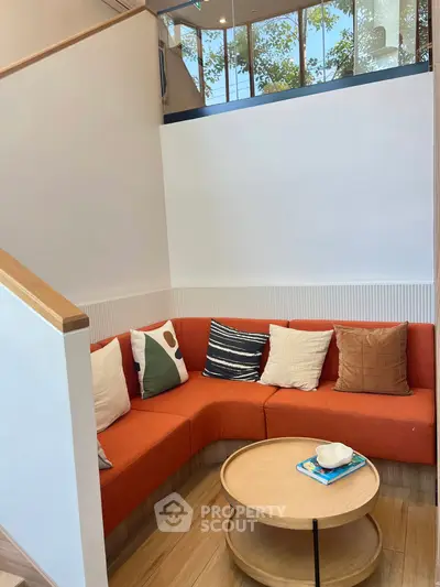 Cozy modern living room with orange sectional sofa and round wooden coffee table, perfect for relaxation.