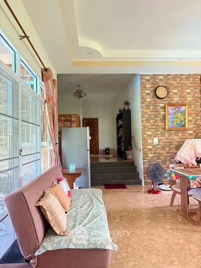 Spacious living room with stylish brick wall and cozy seating area, perfect for relaxation and entertaining.