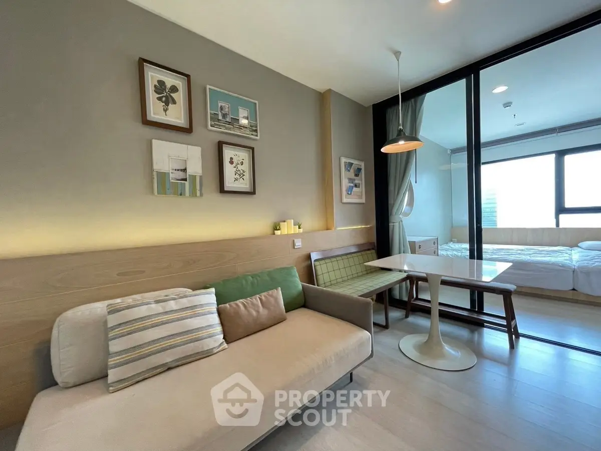 Modern living room with stylish decor and glass partition to bedroom