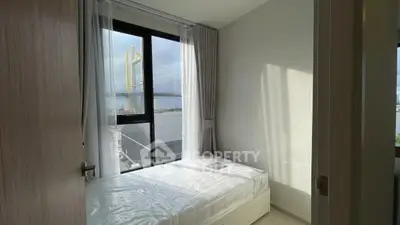 Bright bedroom with large window and modern decor, offering a serene and cozy atmosphere.