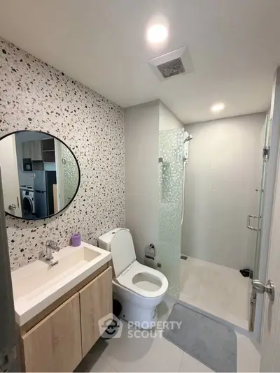 Modern bathroom with terrazzo wall, glass shower, and sleek vanity in contemporary apartment.