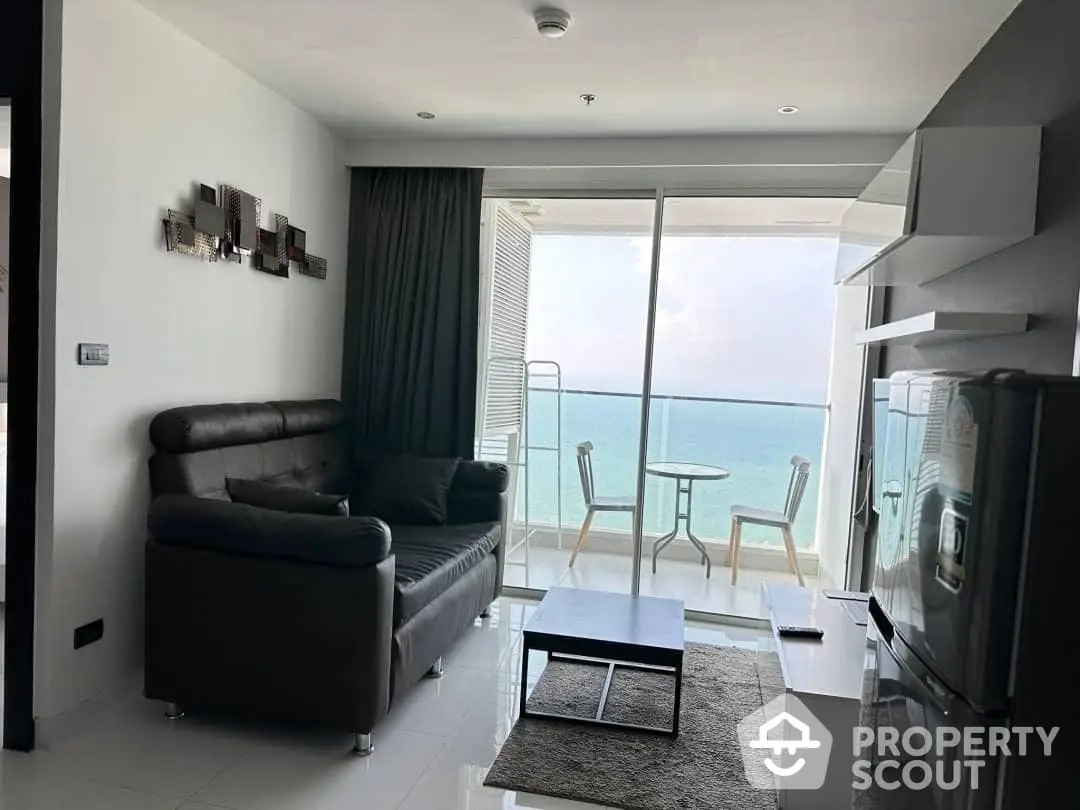 Modern beachfront living room with floor-to-ceiling windows offering a panoramic ocean view, sleek furniture, and a cozy ambiance.