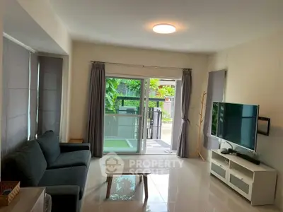 Spacious living room with modern decor and large windows opening to a lush garden view.