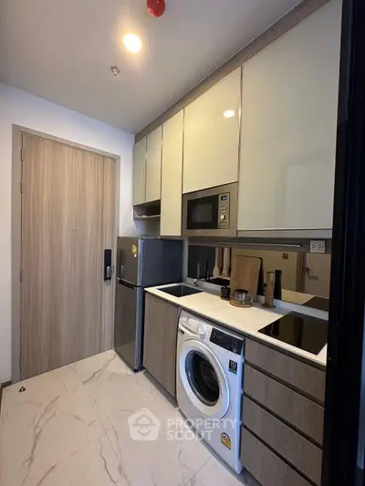 Modern kitchen with sleek appliances and washing machine in compact layout