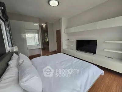 Spacious modern bedroom with sleek furniture and large TV, perfect for relaxation and comfort.