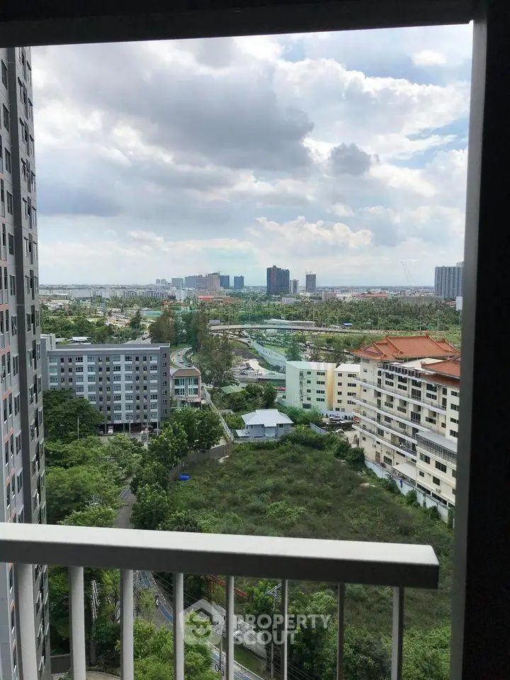 Stunning cityscape view from a high-rise balcony overlooking lush greenery and urban skyline.