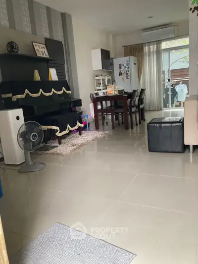 Spacious living room with modern decor and natural light, featuring a dining area and large window.