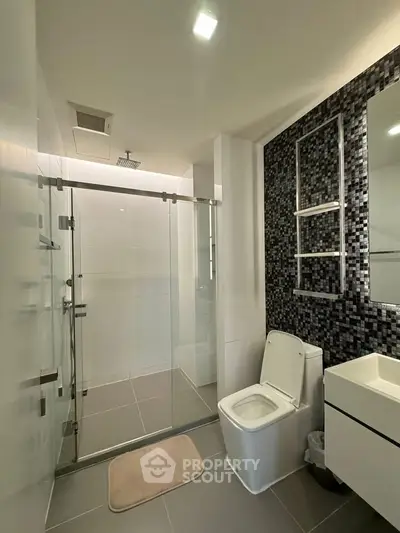 Modern bathroom with glass shower, sleek tiles, and contemporary fixtures.