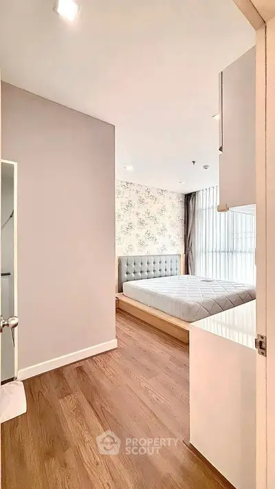 Modern bedroom with elegant design and wooden flooring, featuring a stylish bed and large window for natural light.