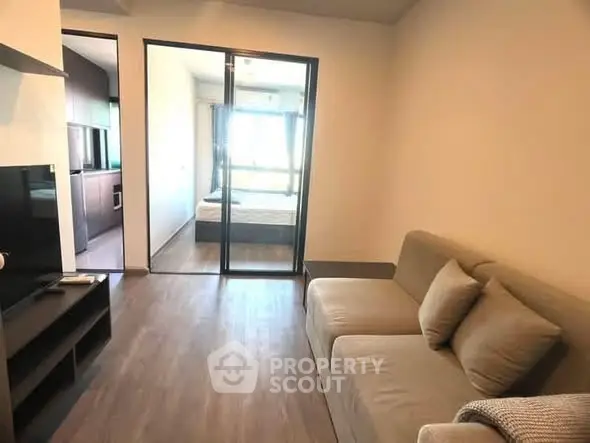 Modern living room with cozy sofa and glass partition leading to bedroom