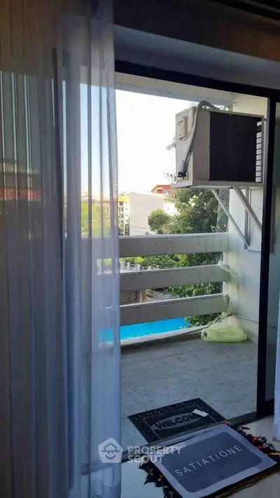 Charming balcony view with sliding glass door and pool glimpse, perfect for relaxation.