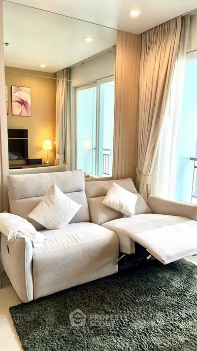 Cozy living room with plush sofa and large window, offering a bright and inviting atmosphere.