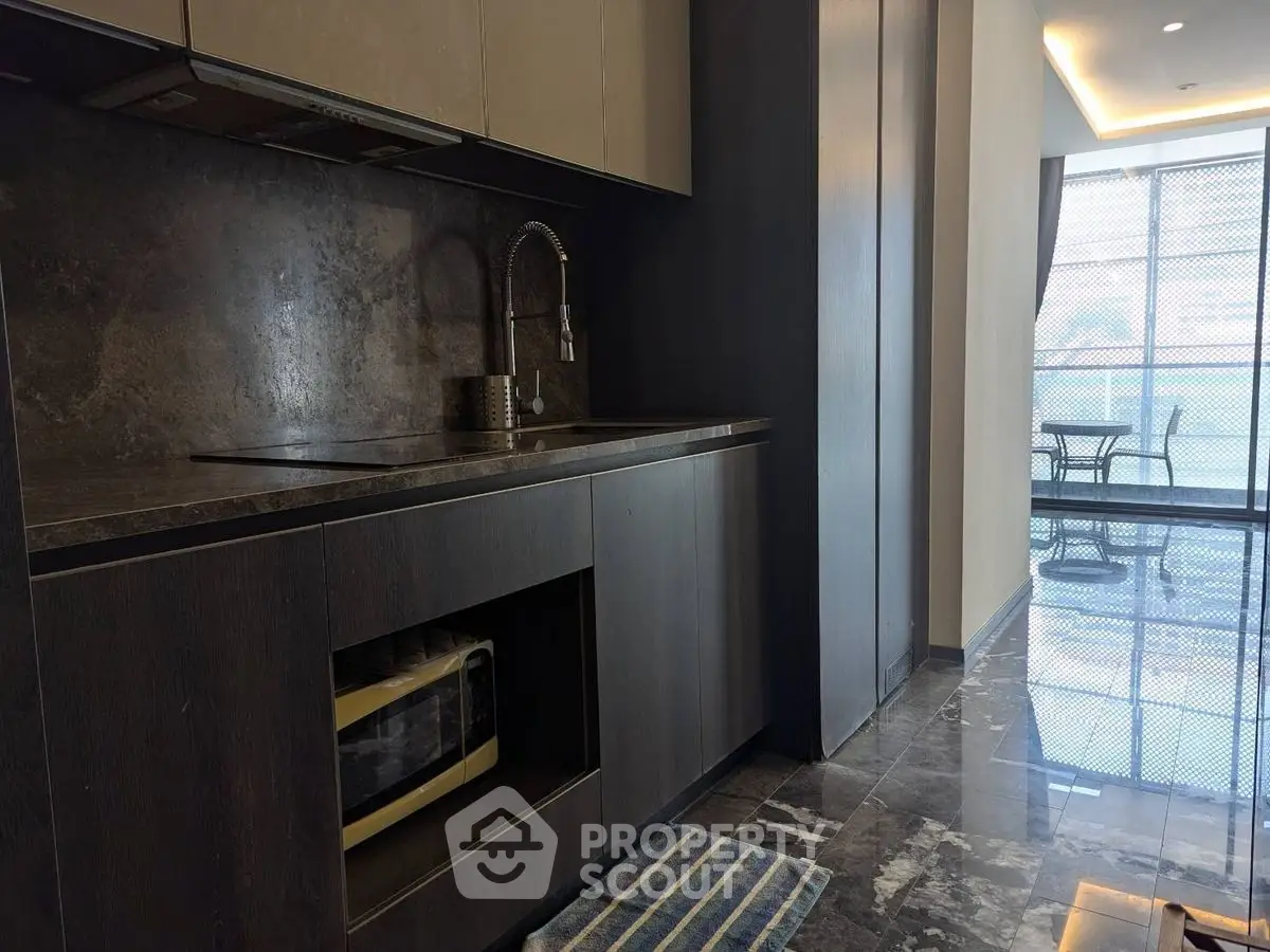 Modern kitchen with sleek dark cabinetry and marble flooring