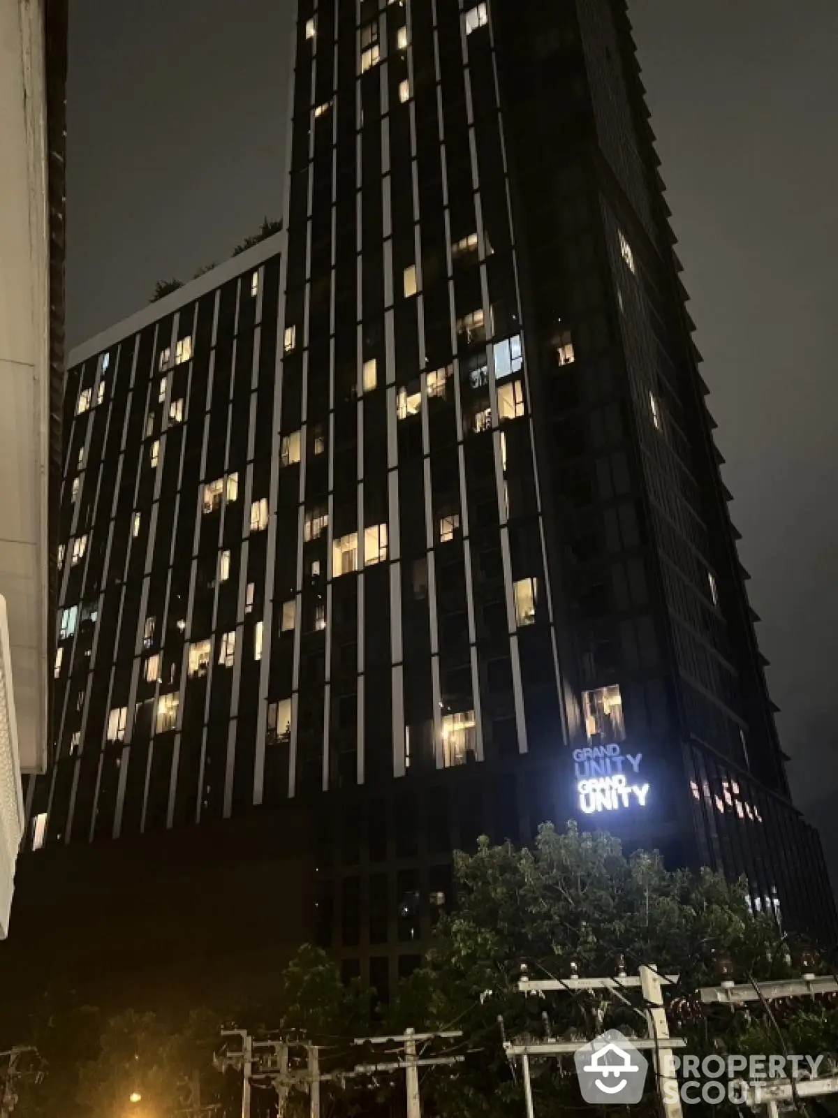 Modern high-rise building at night with illuminated windows and sleek design.